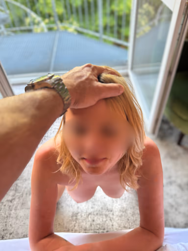 Escort Lady Matilda kniet nackt vor einem geöffneten Balkonfenster. Eine männliche Hand liegt fest auf ihrem Kopf, während sie ergeben nach oben blickt. Ihr nackter Körper strahlt Hingabe und Bereitschaft aus, sich vollständig hinzugeben. Die Szene weckt die Fantasie, wie sie sich dem Mann völlig ausliefert, bereit für leidenschaftliche und dominante Spiele. Matilda Escort Magdeburg zeigt hier ihre devote Seite voller Erotik und Lust.